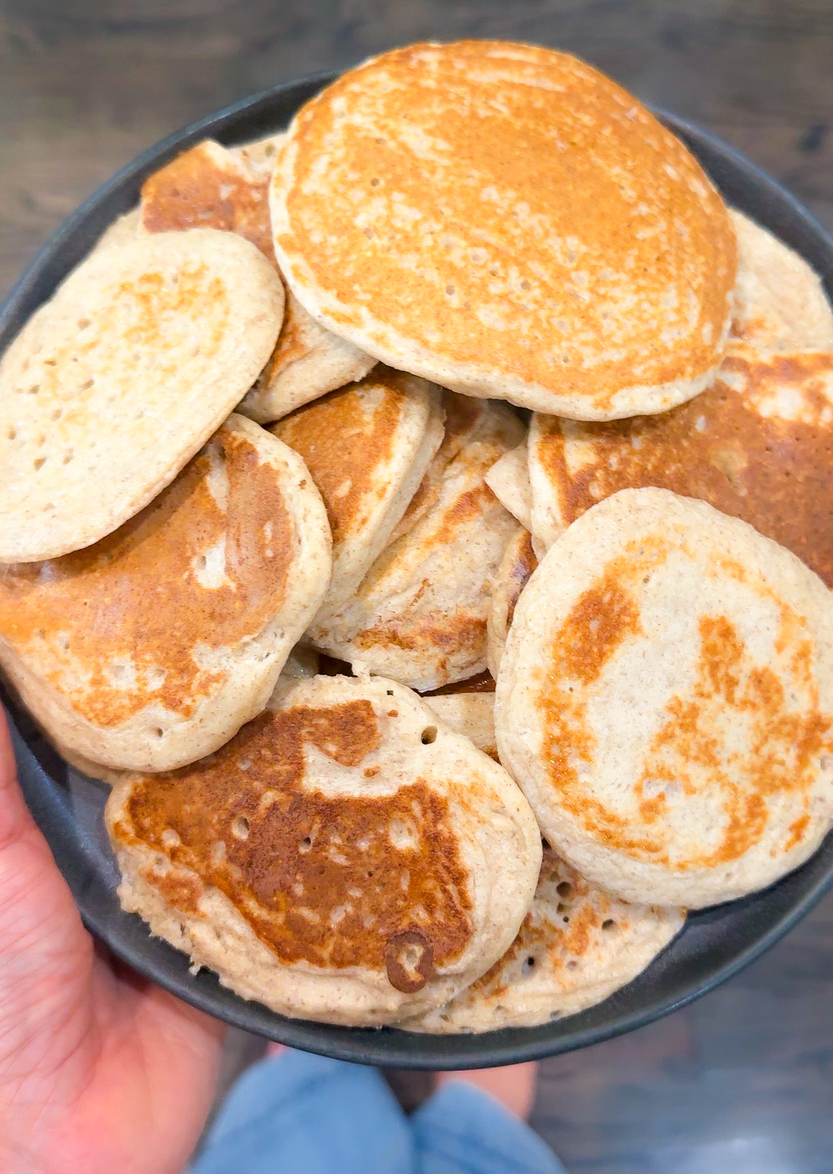 Overhead shot of golden brown homemade protein pancakes piled on a black plate
